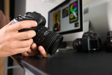 Photo of Photographer with professional camera at black desk indoors, closeup