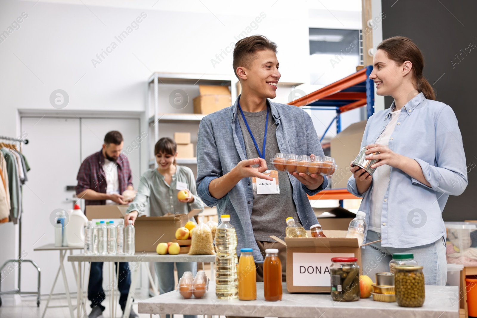 Photo of Volunteers packing food donations at tables indoors, selective focus