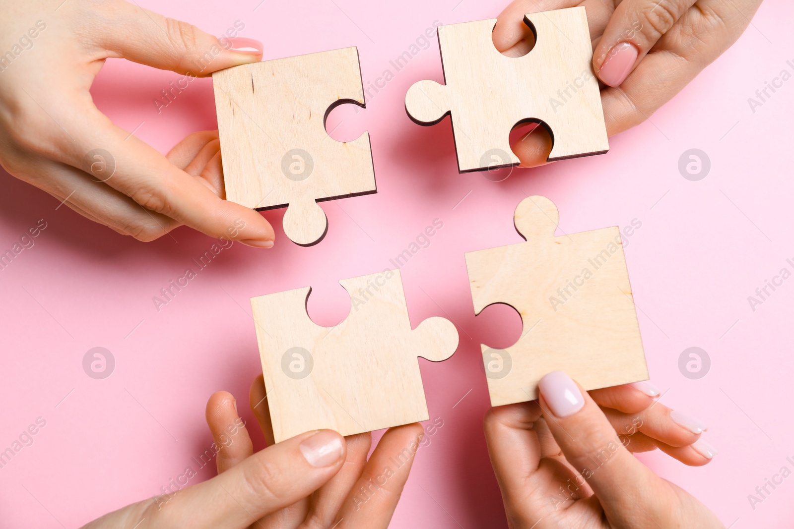 Photo of Business strategy and teamwork concept. Group of businesspeople putting puzzle pieces together on pink background, top view