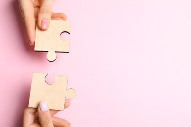 Photo of Business strategy and teamwork concept. Partners putting puzzle pieces together on pink background, top view with space for text