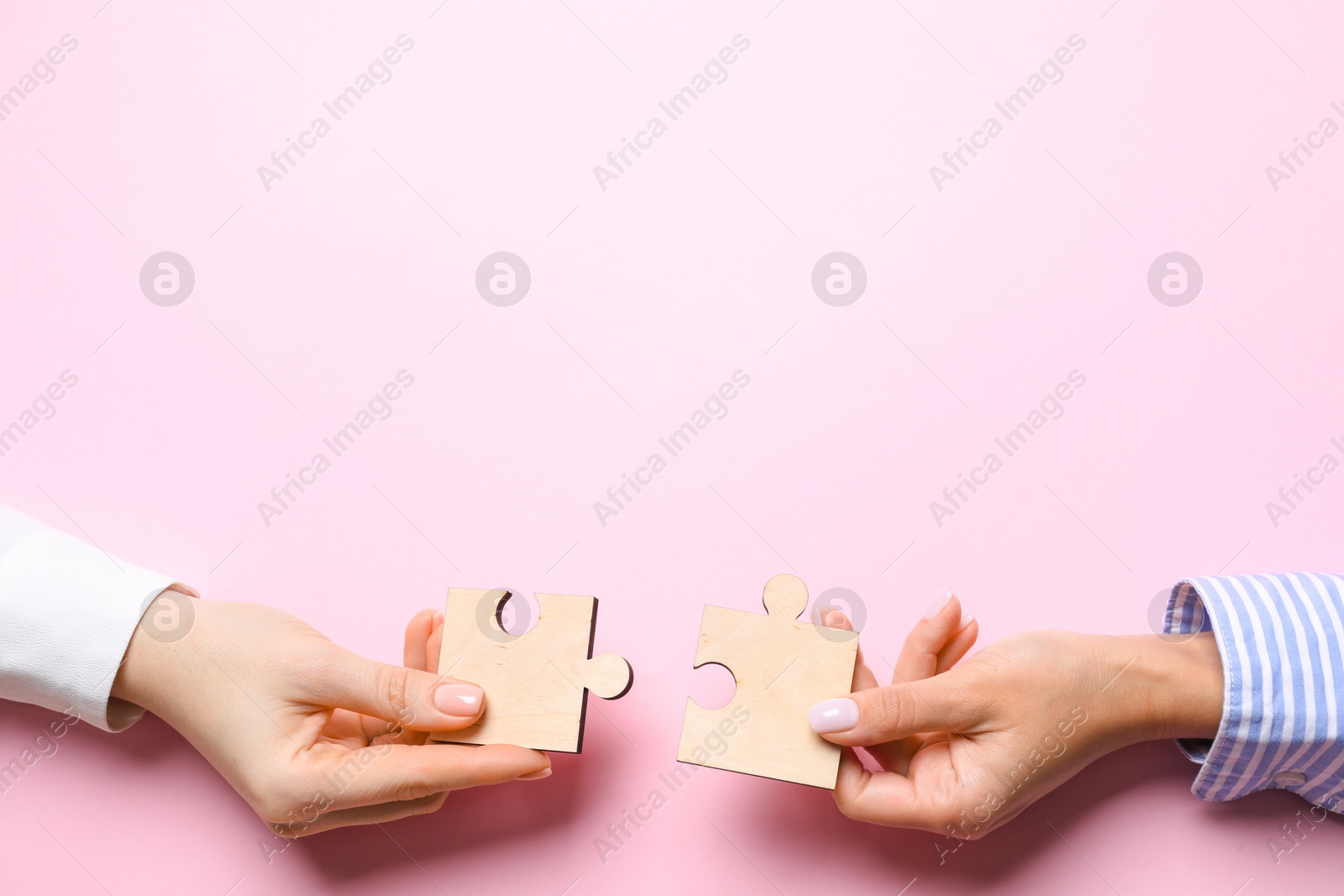 Photo of Business strategy and teamwork concept. Partners putting puzzle pieces together on pink background, top view with space for text