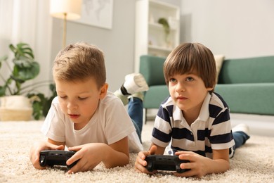 Photo of Cute brothers playing video game on floor at home