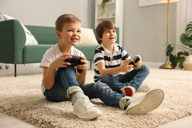 Photo of Cute brothers playing video game on floor at home