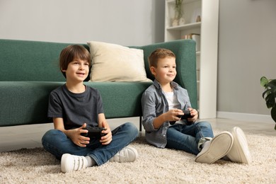 Photo of Cute brothers playing video game on floor at home