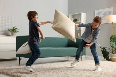 Photo of Brothers having fun pillow fight at home