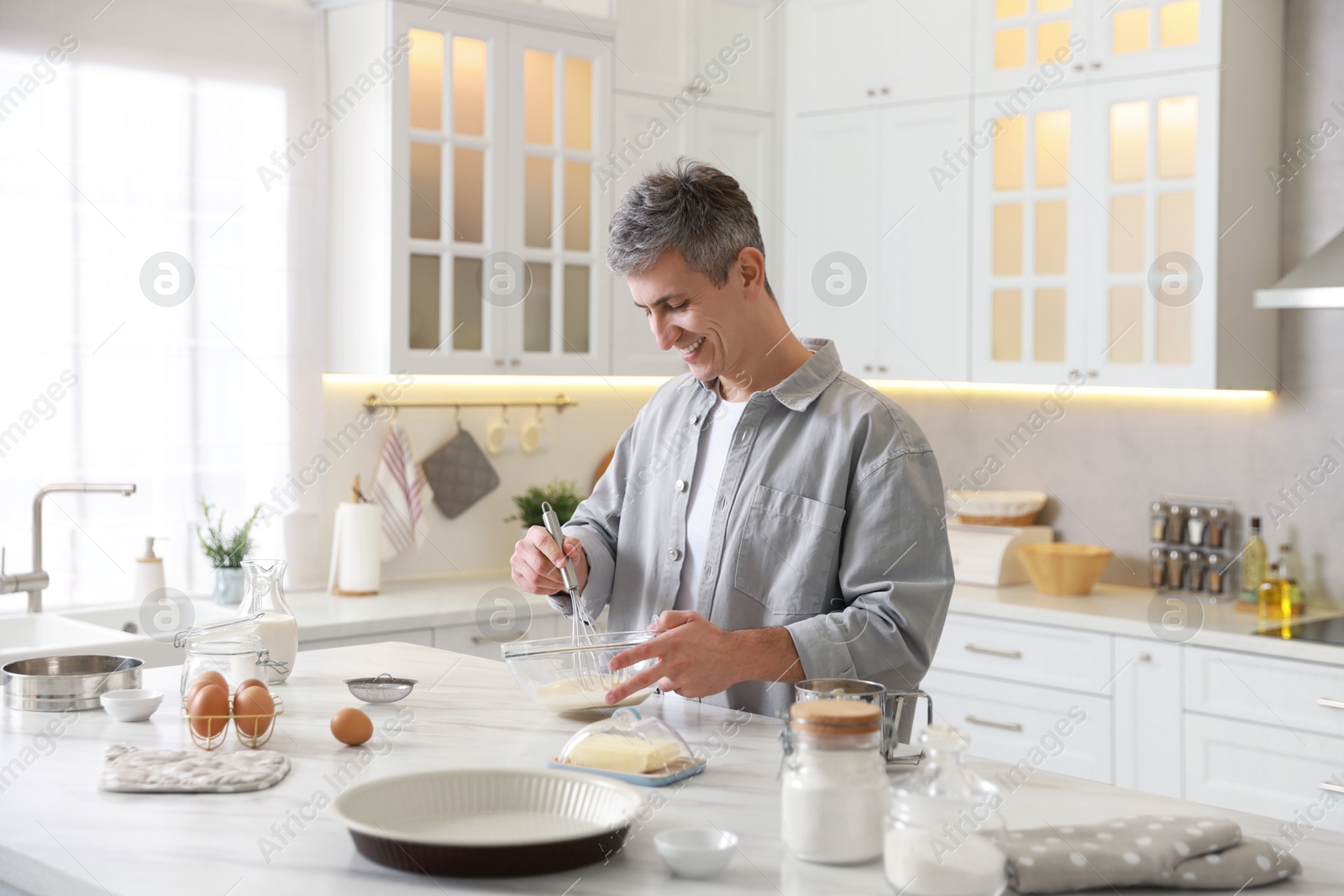 Photo of Man making dough at white marble table in kitchen