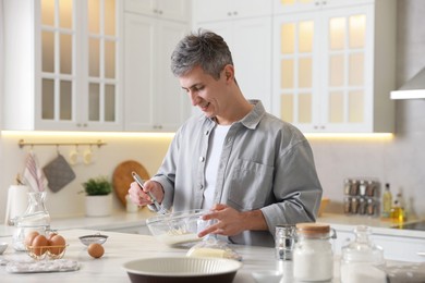 Photo of Man making dough at white marble table in kitchen