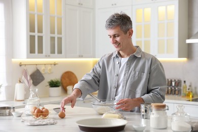 Photo of Man making dough at white marble table in kitchen