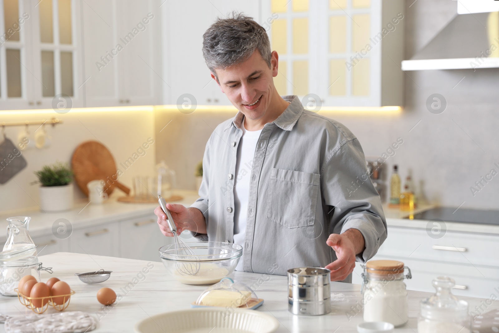 Photo of Man making dough at white marble table in kitchen