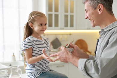 Photo of Father and his daughter making dough in kitchen