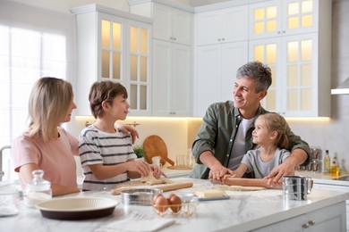 Photo of Happy family making dough at white marble table in kitchen