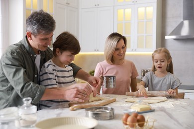 Photo of Happy family making dough at white marble table in kitchen