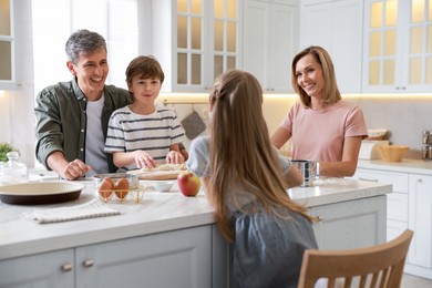 Photo of Happy family making dough at white marble table in kitchen