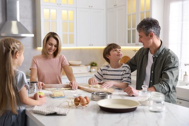 Photo of Happy family making dough at white marble table in kitchen