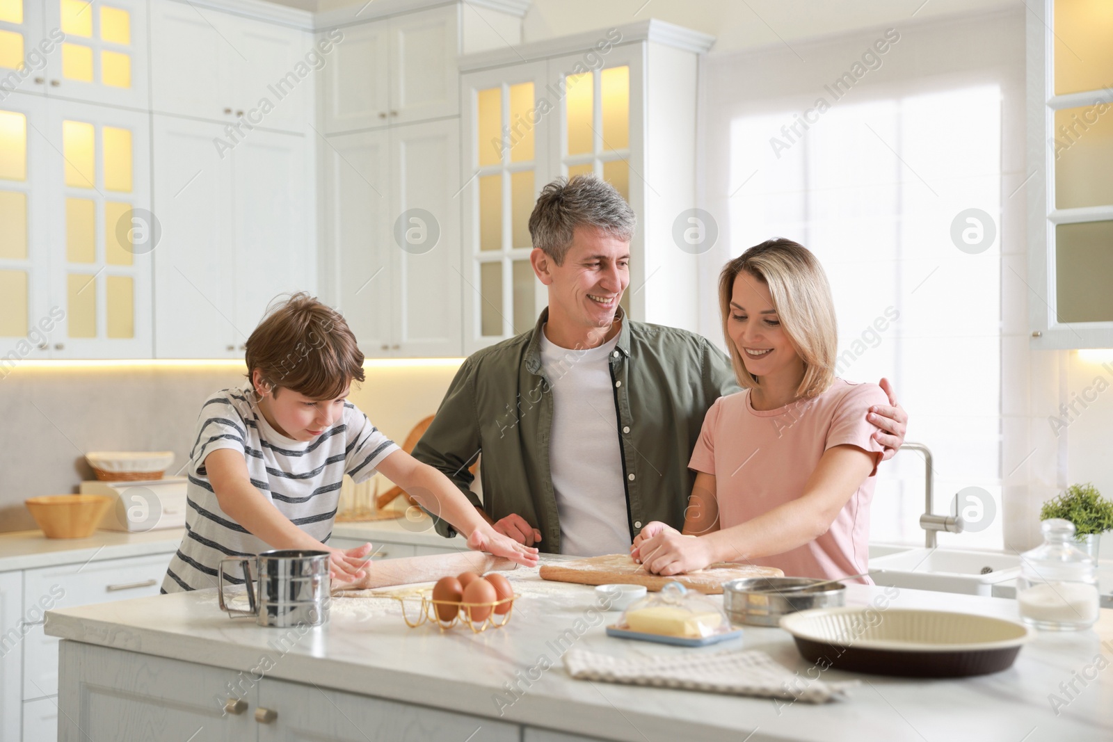 Photo of Happy family kneading dough at white marble table in kitchen