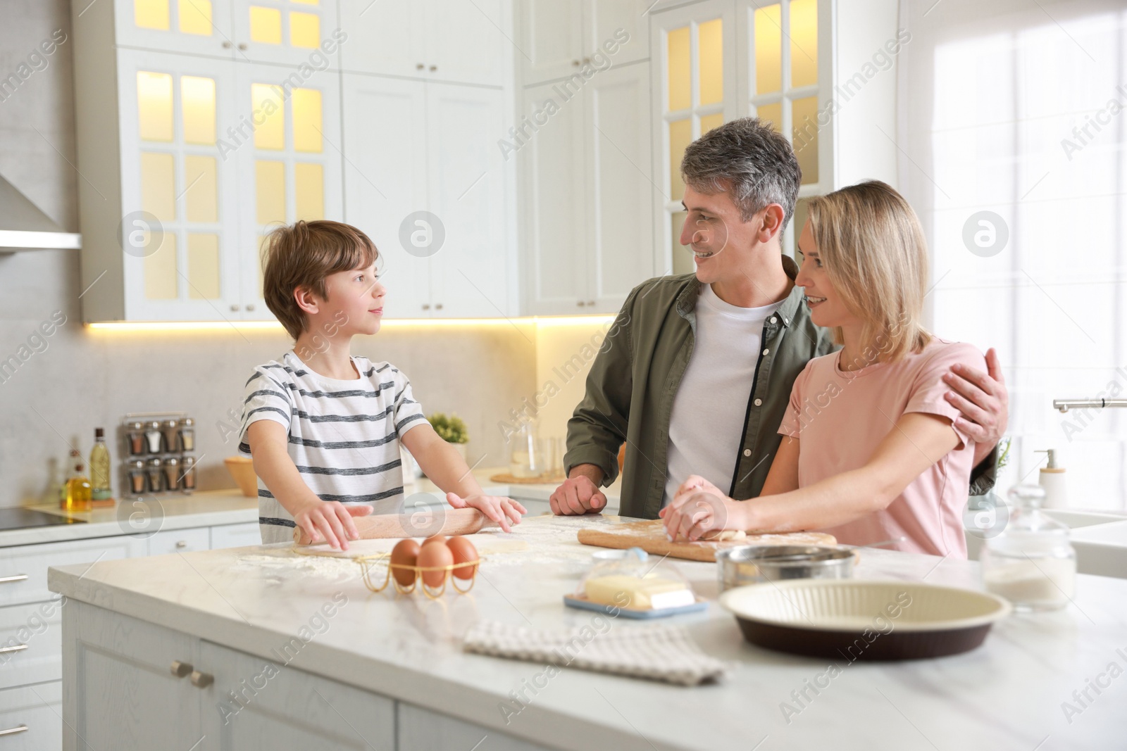 Photo of Happy family kneading dough at white marble table in kitchen