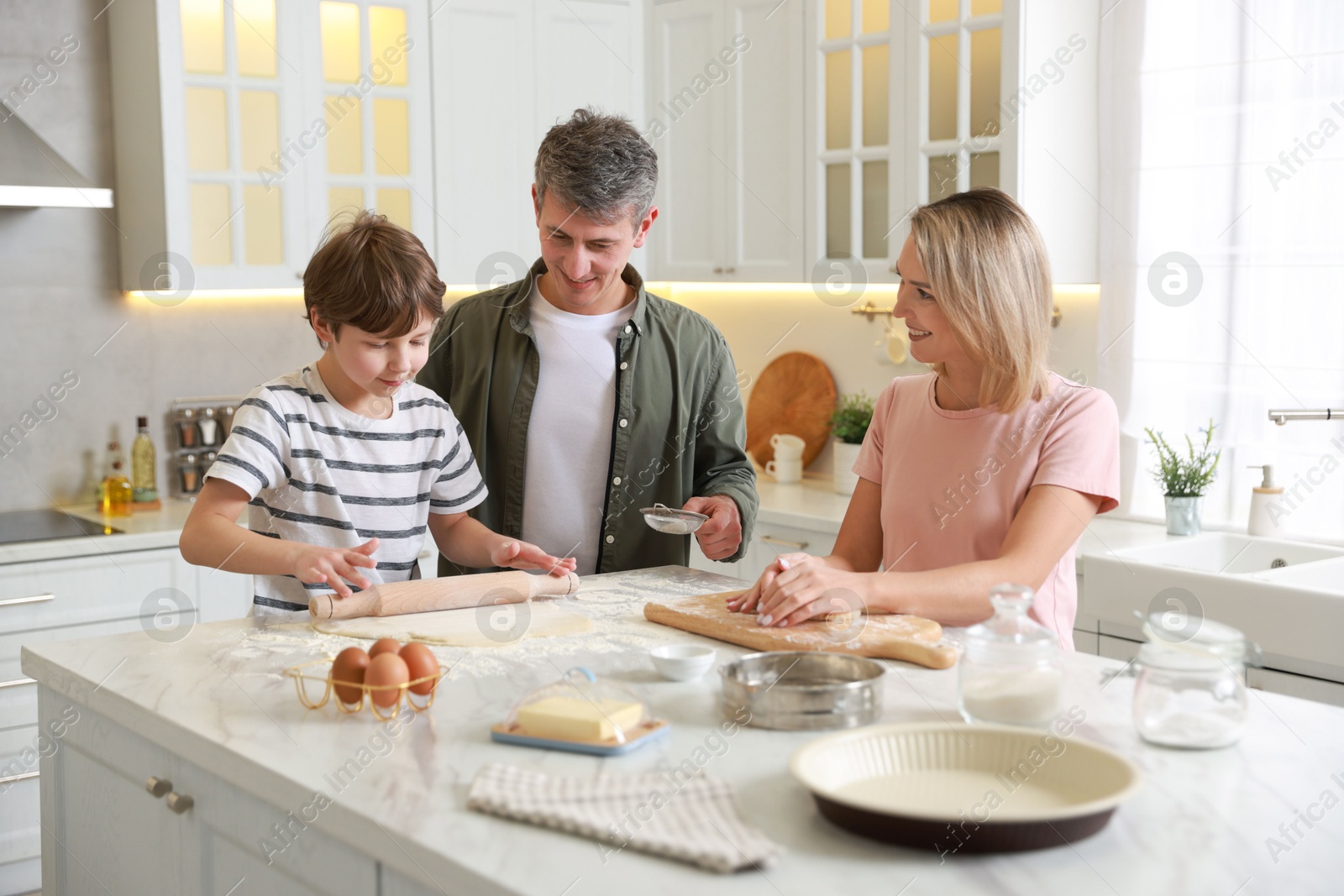 Photo of Happy family kneading dough at white marble table in kitchen