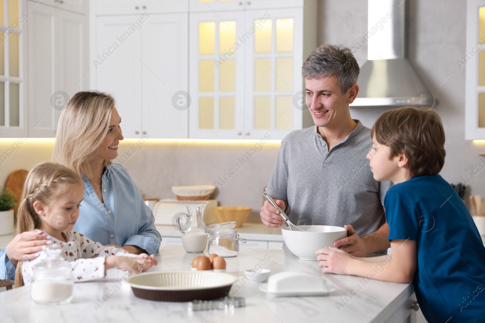 Photo of Happy family making dough at white marble table in kitchen