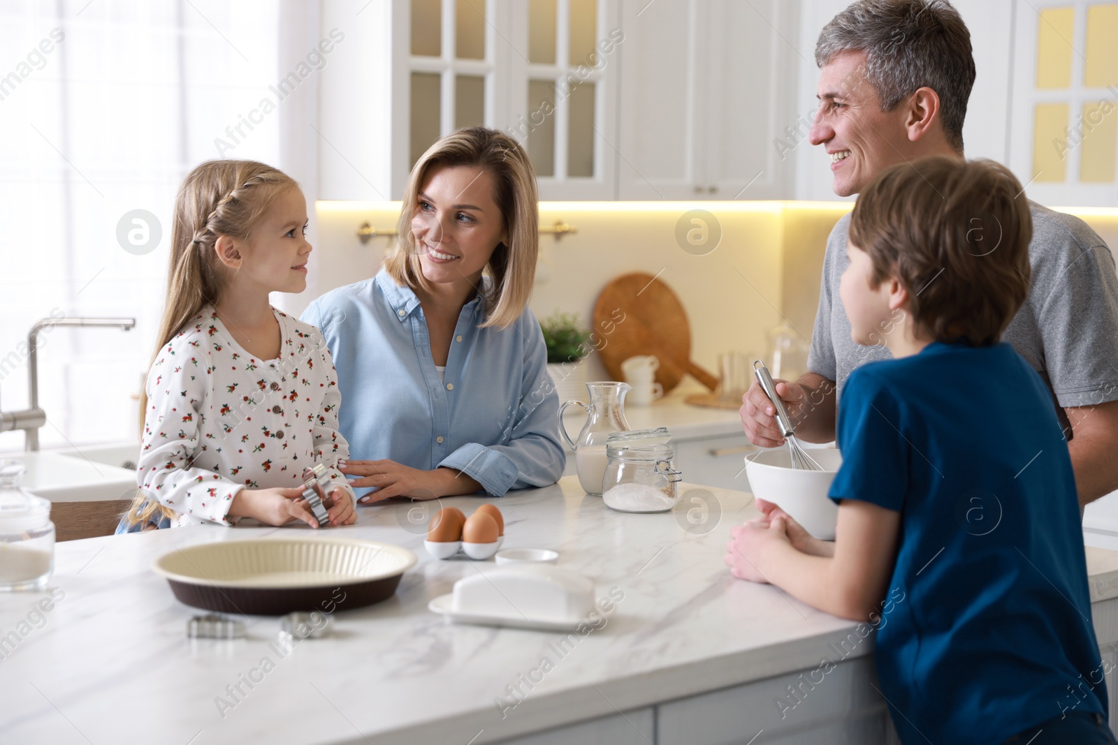 Photo of Happy family making dough at white marble table in kitchen