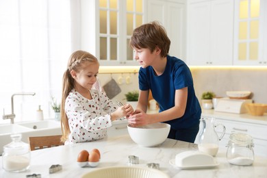 Little kids making dough at white marble table in kitchen