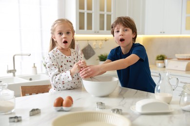 Little kids making dough at white marble table in kitchen