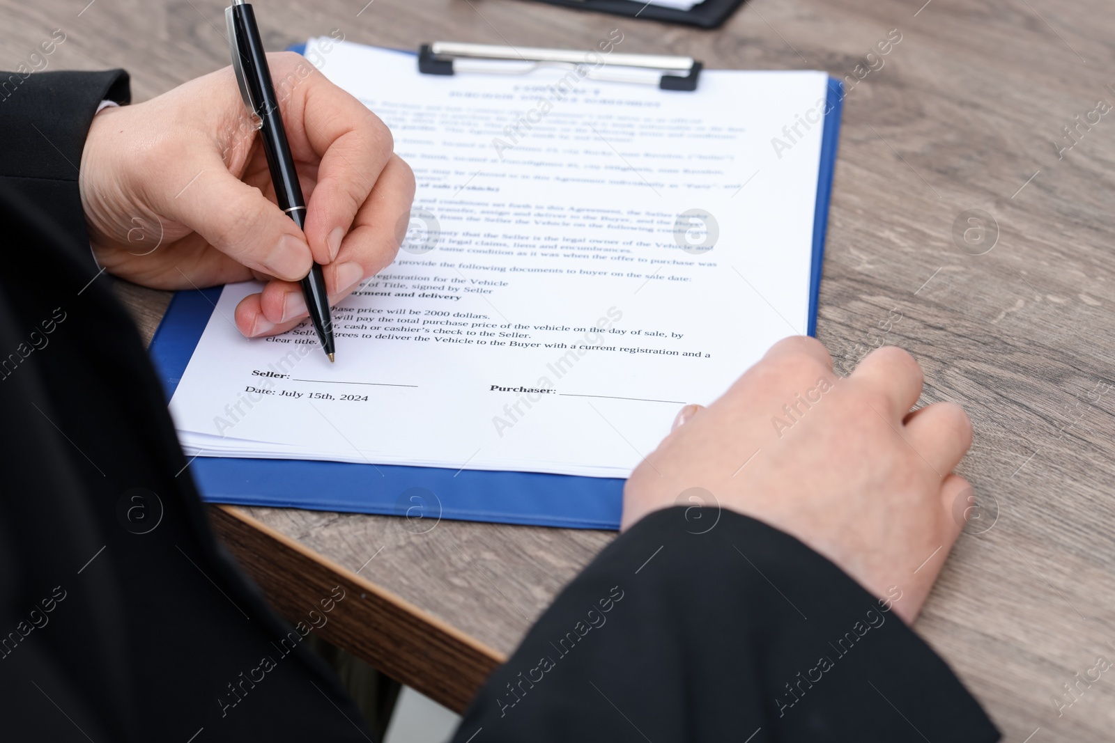 Photo of Man signing car purchase agreement at wooden table, closeup. Buying auto