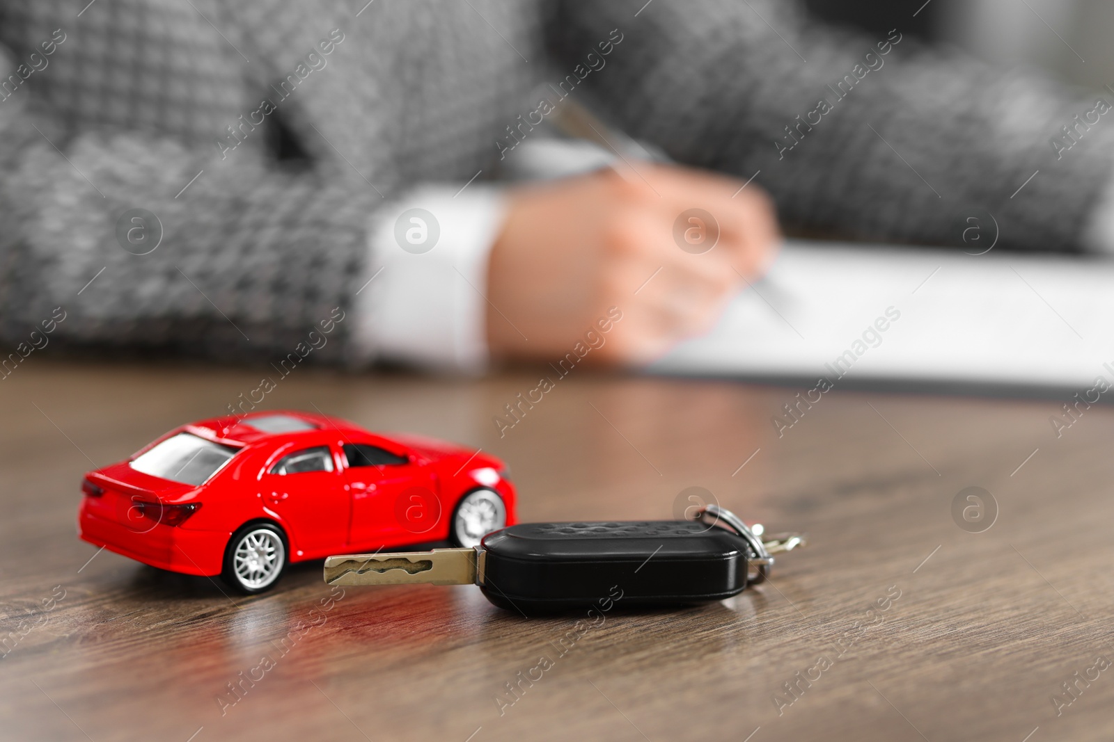 Photo of Client signing car purchase agreement at wooden table, selective focus. Buying auto