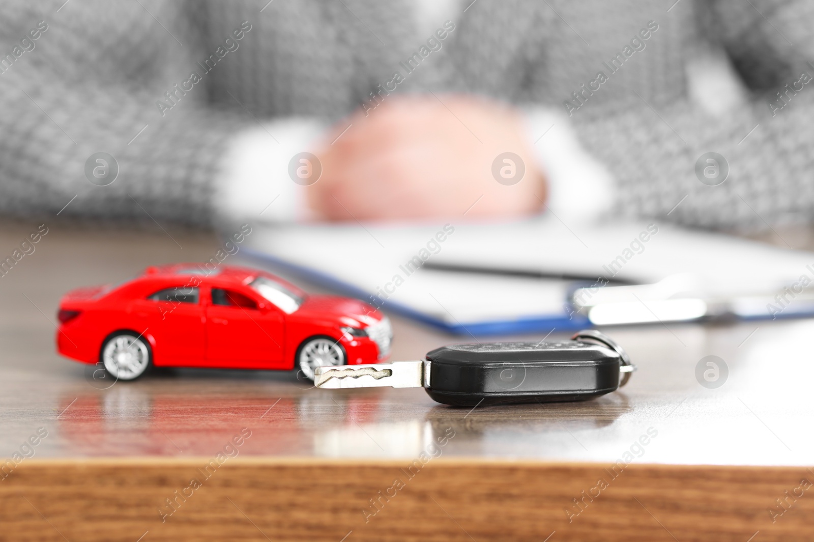 Photo of Car model and key on wooden table, selective focus. Buying auto