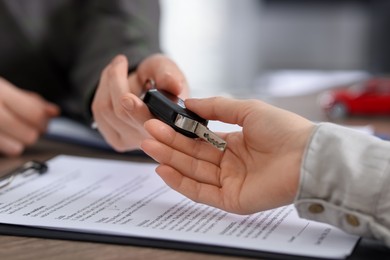 Photo of Buying auto. Client getting car key at table, closeup