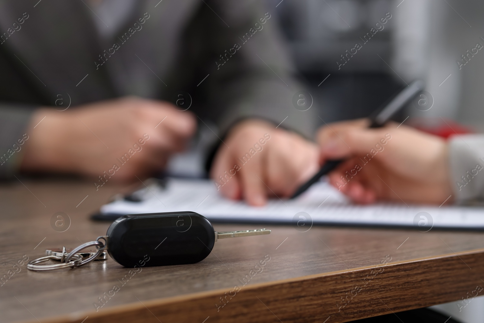 Photo of Manager and client signing car purchase agreement at wooden table, selective focus. Buying auto