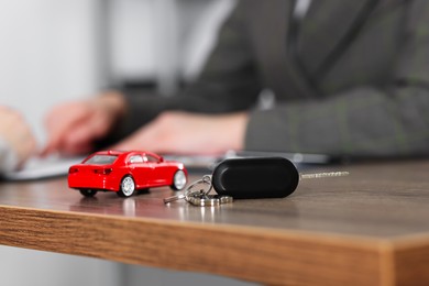 Photo of Manager and client signing car purchase agreement at wooden table, selective focus. Buying auto