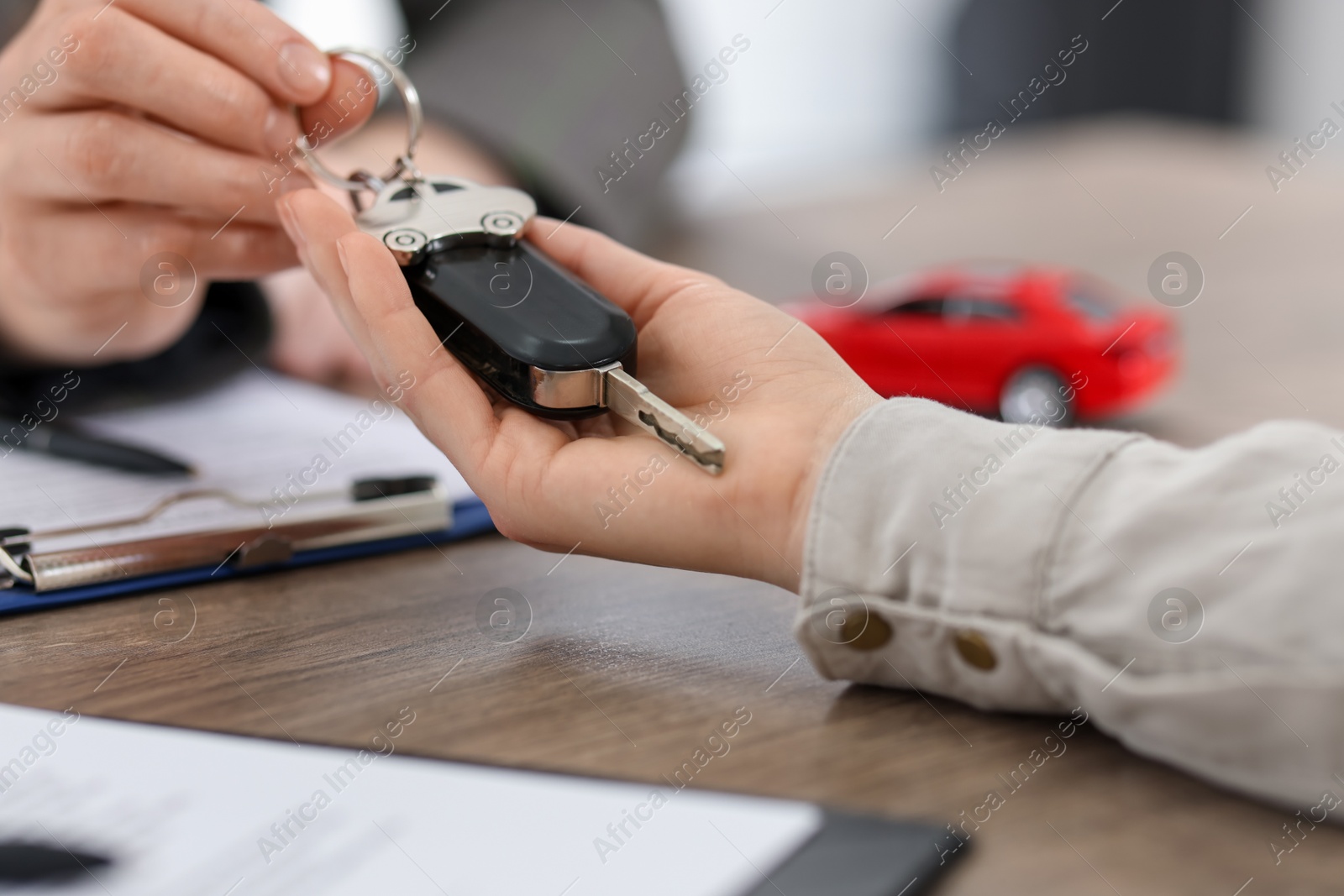 Photo of Buying auto. Client getting car key at wooden table, closeup