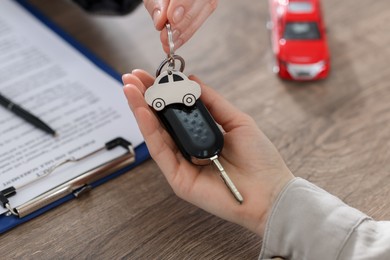 Photo of Buying auto. Client getting car key at wooden table, closeup