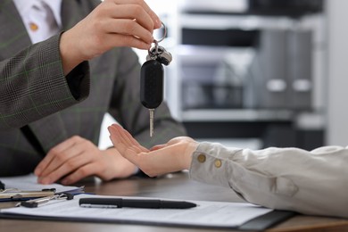 Photo of Buying auto. Client getting car key at table, closeup