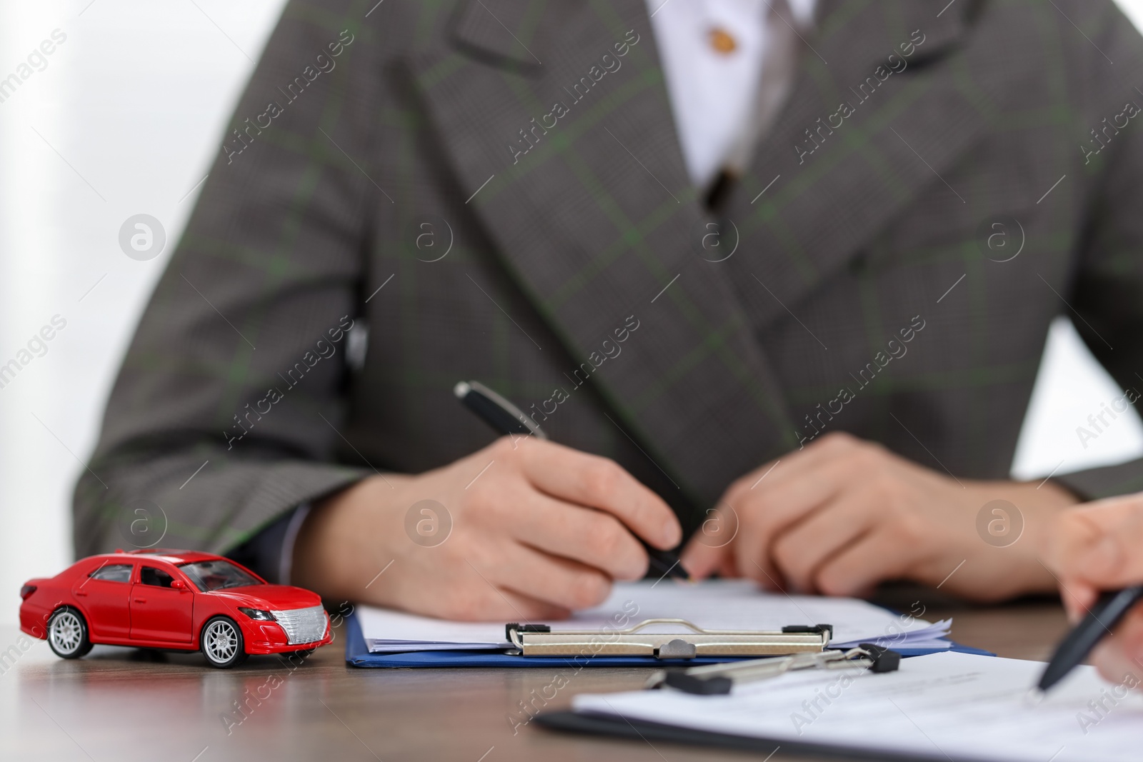 Photo of Manager and client signing car purchase agreement at wooden table, selective focus. Buying auto