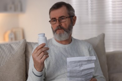 Photo of Senior man with bottle of pills and instruction at home, selective focus