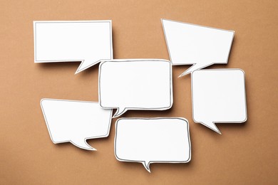 Photo of Blank speech bubbles on brown background, top view. Space for text