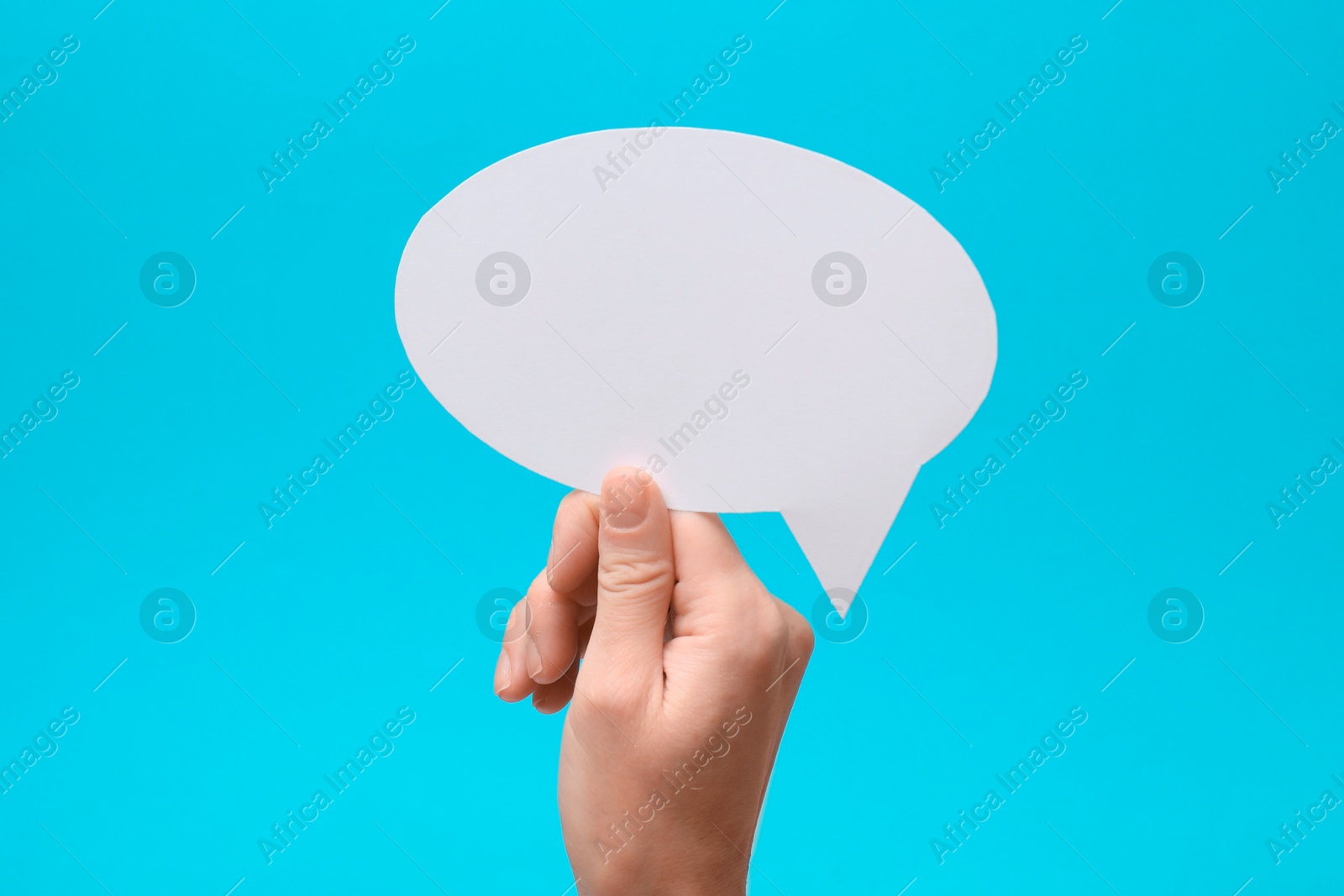 Photo of Woman holding blank speech bubble on light blue background, closeup. Space for text