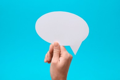 Photo of Woman holding blank speech bubble on light blue background, closeup. Space for text