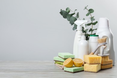 Photo of Eco-friendly cleaning products, supplies and eucalyptus branches on wooden table, space for text