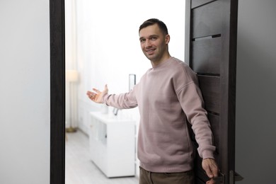 Photo of Cheerful man welcoming guests to his apartment