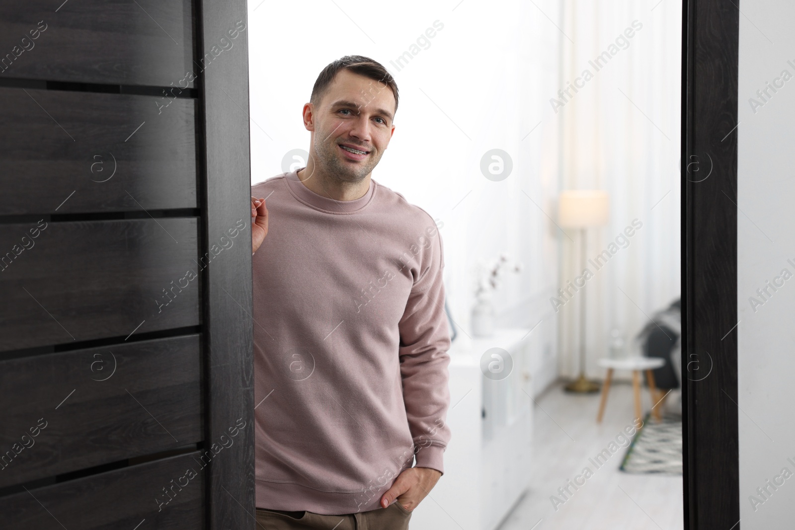 Photo of Cheerful man welcoming guests to his apartment. Space for text