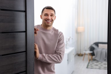 Photo of Cheerful man welcoming guests to his apartment. Space for text