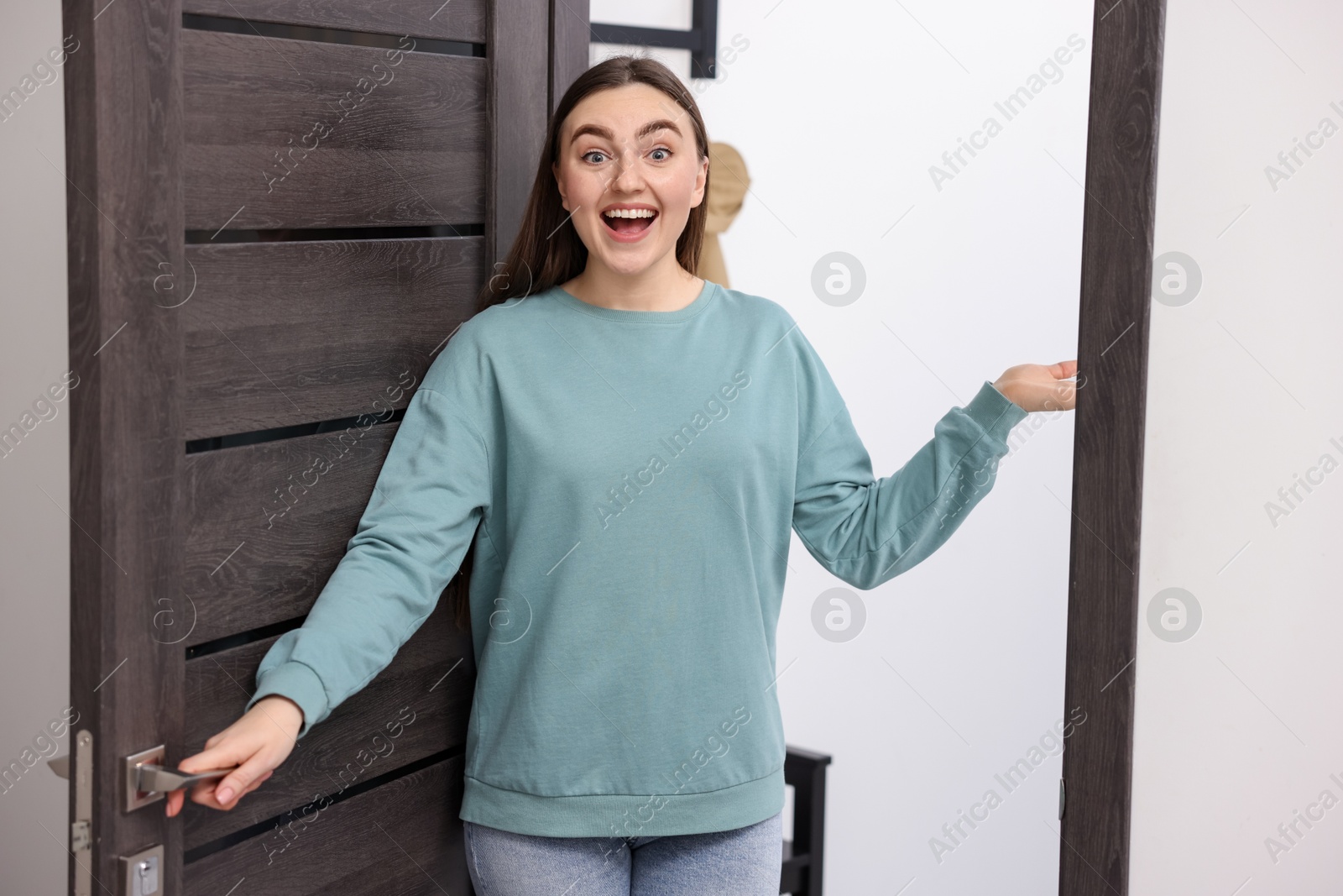 Photo of Excited woman welcoming guests to her apartment