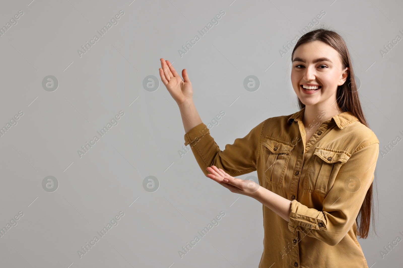 Photo of Woman welcoming friends or guests on grey background. Space for text