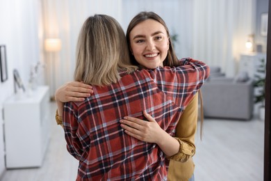 Photo of Happy woman welcoming friend to her apartment