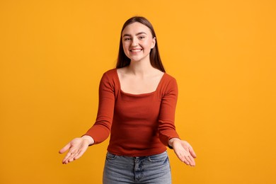 Photo of Happy woman welcoming guests on orange background