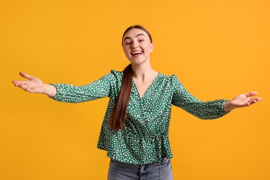 Photo of Cheerful woman welcoming guests on orange background