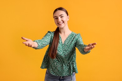 Photo of Cheerful woman welcoming guests on orange background