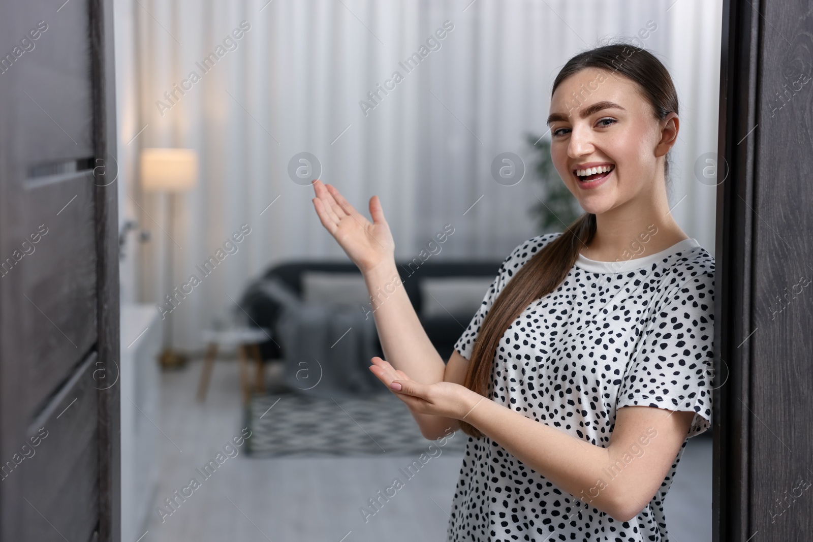 Photo of Happy woman welcoming guests to her house